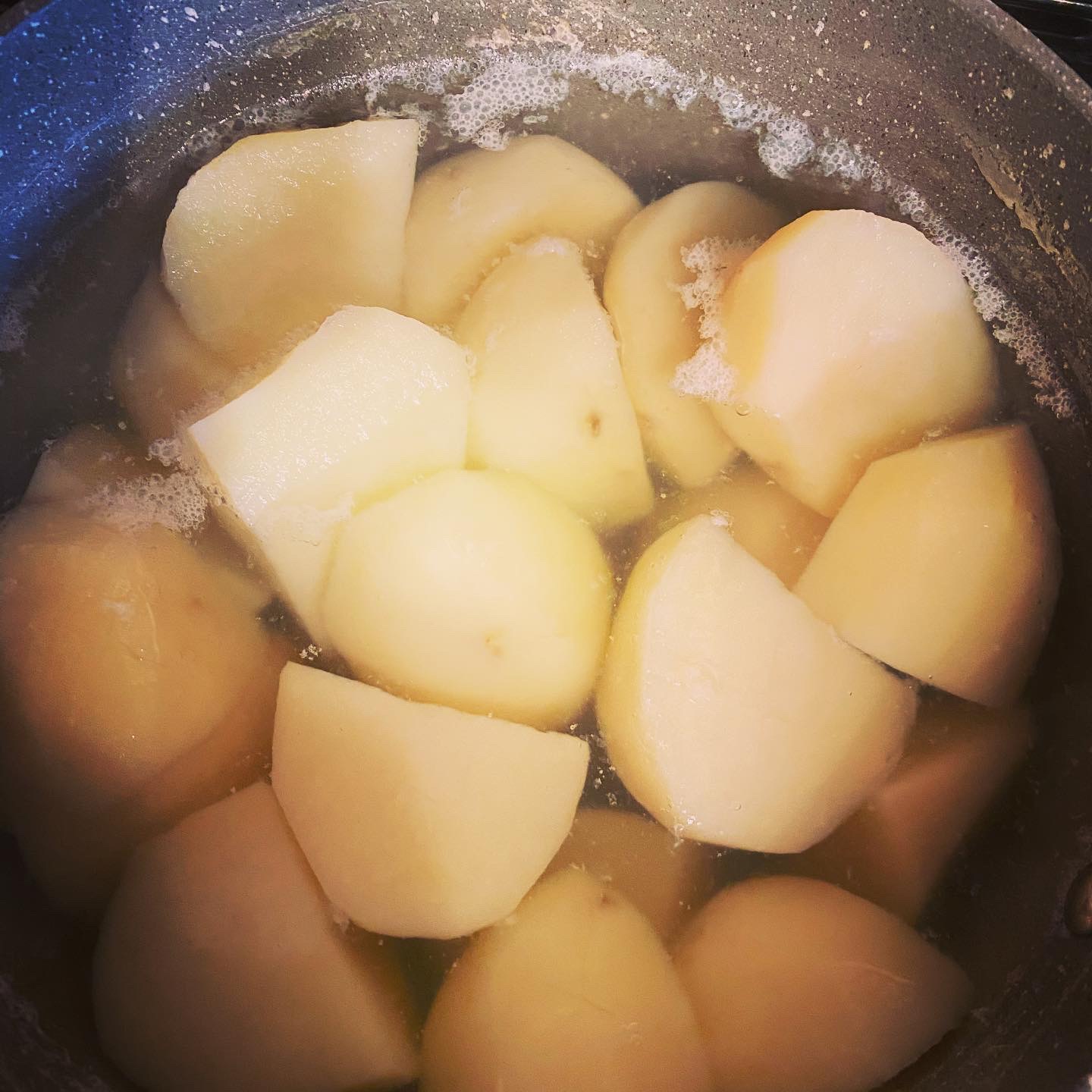 Peeled potatoes simmering in water during the parboiling stage for roast potatoes.